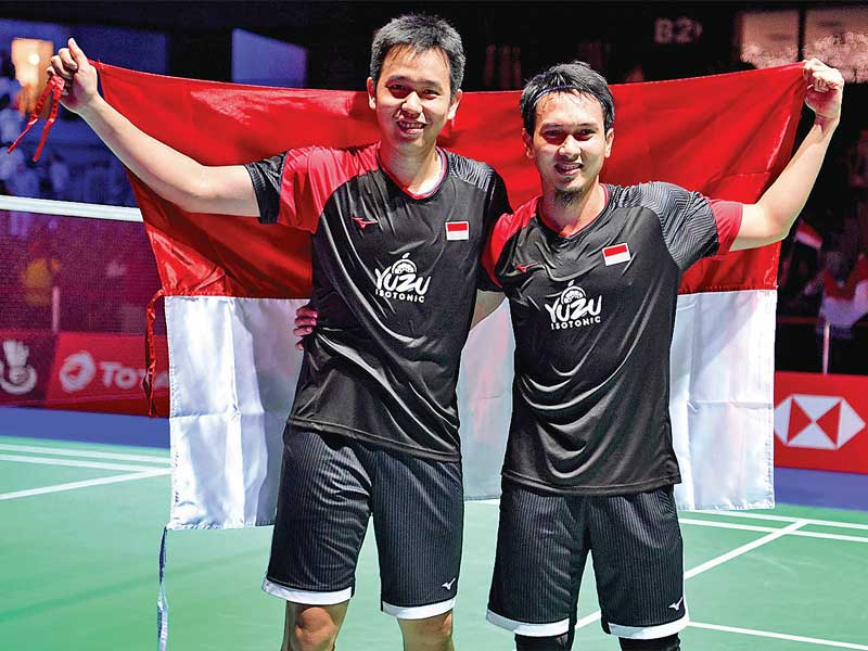 Ganda Putra Indonesia, Hendra Setiawan (kiri) dan Mohammad Ahsan, membawa bendera Merah Putih menjadi Juara Dunia 2019 