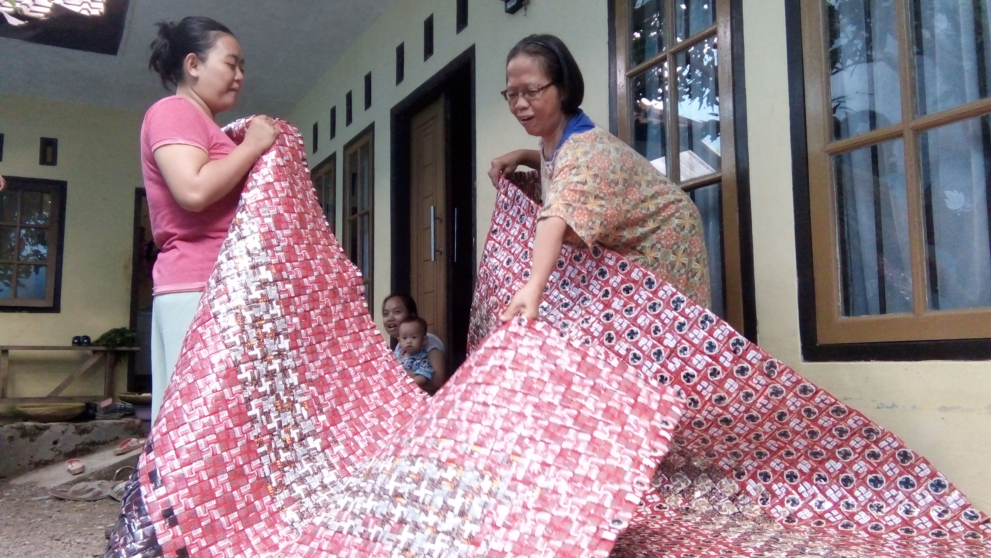 Ibu-ibu warga Kampung Cikalang Desa memanfaatkan bungkus kopi menjadi kerajinan. Salah satunya adalah karpet. 