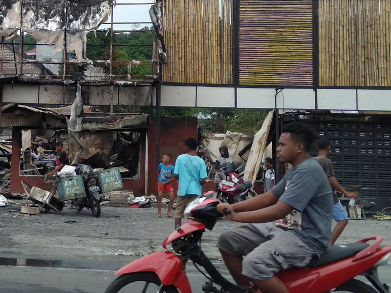 Warga membersihkan puing sisa kerusuhan di salah satu gedung yang terbakar di Manokwari, Papua Barat.
