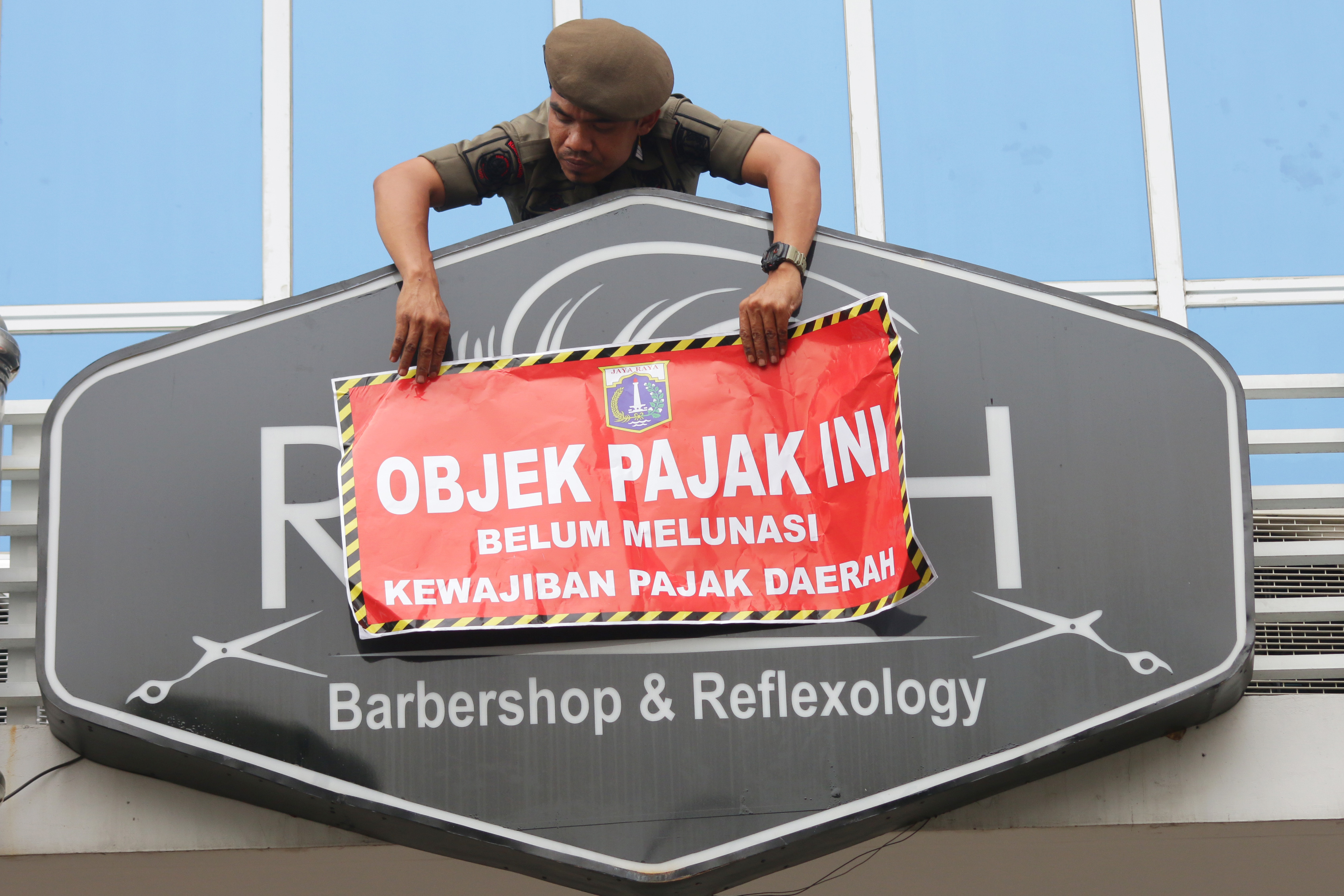 Petugas memasang stiker tertib objek pajak terhadap sejumlah tempat di kawasan Green Pramuka Square, Jakarta.