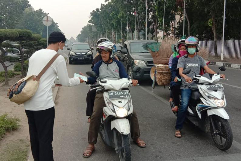 Anggota Kutu Community membagikan masker kepada pengguna jalan di Pekanbaru, Riau
