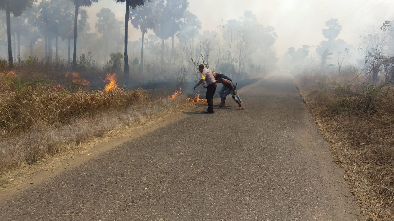 Personel kepolisian dibantu warga sedang berupaya memadamkan api di kawasan hutan