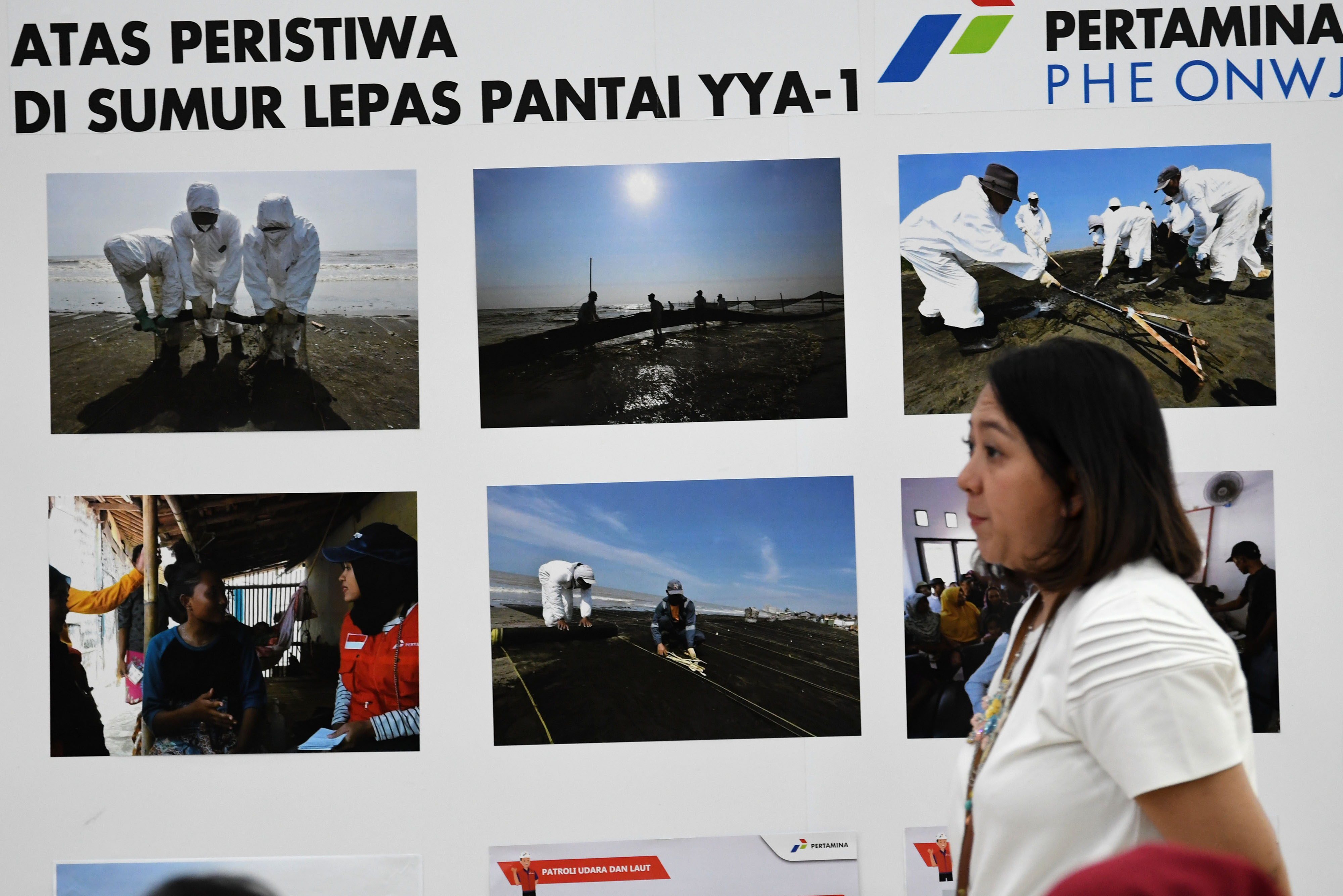 Karyawan melintasi foto-foto dokumentas penanganan kebocoran Sumur Lepas Pantai YYA-1 di Kantor Pusat Pertamina, Jakarta, Jumat (20/9).