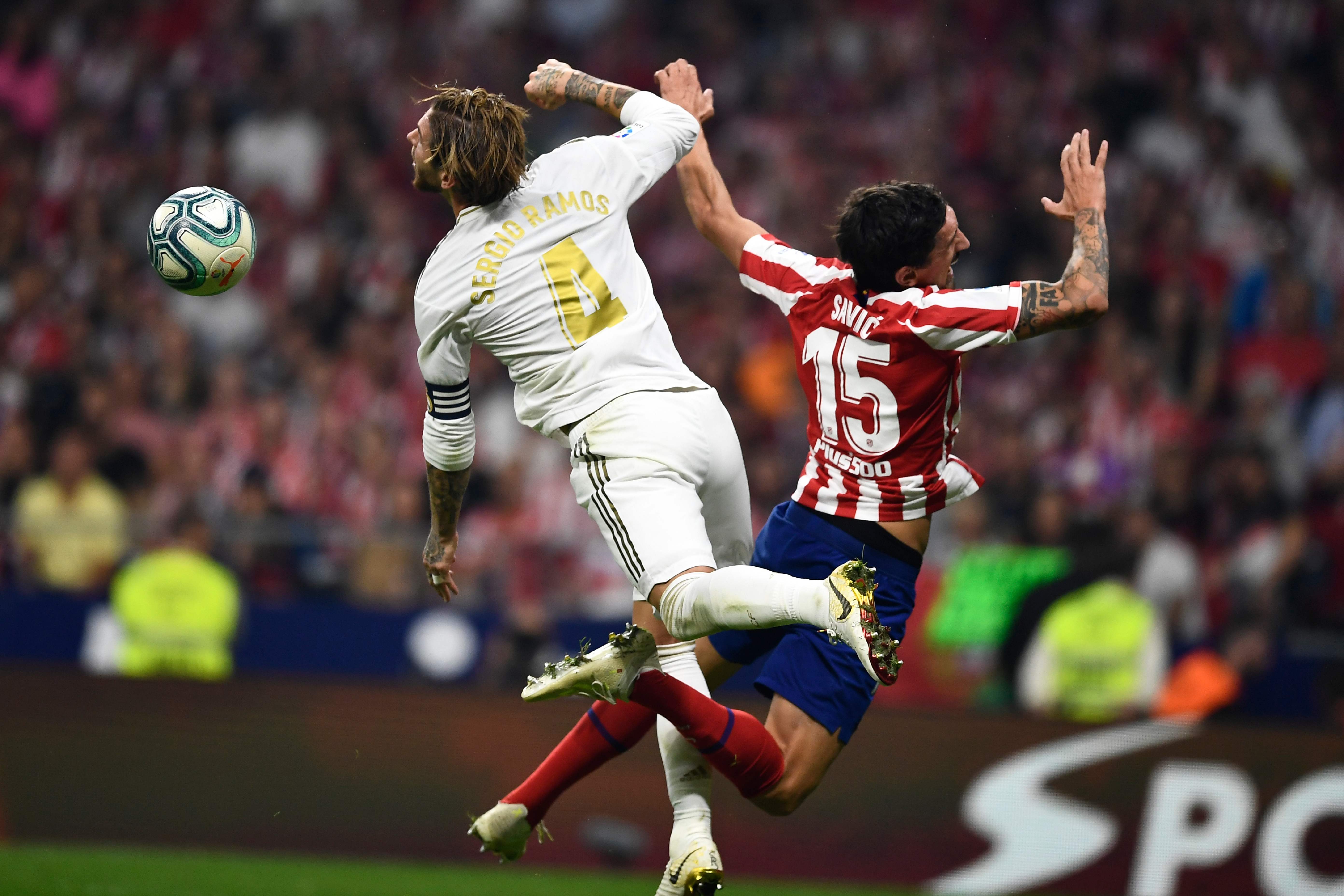 Bek Real Madrid Sergio Ramos (kiri) dan bek Atletico Madrid Stefan Savic berebut bola dalam laga lanjutan La Liga