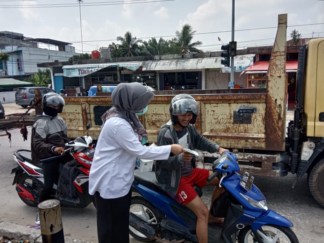 Petugas kesehatan membagikan masker kepada pengendara motor di Kota Pekanbaru, Riau. 
