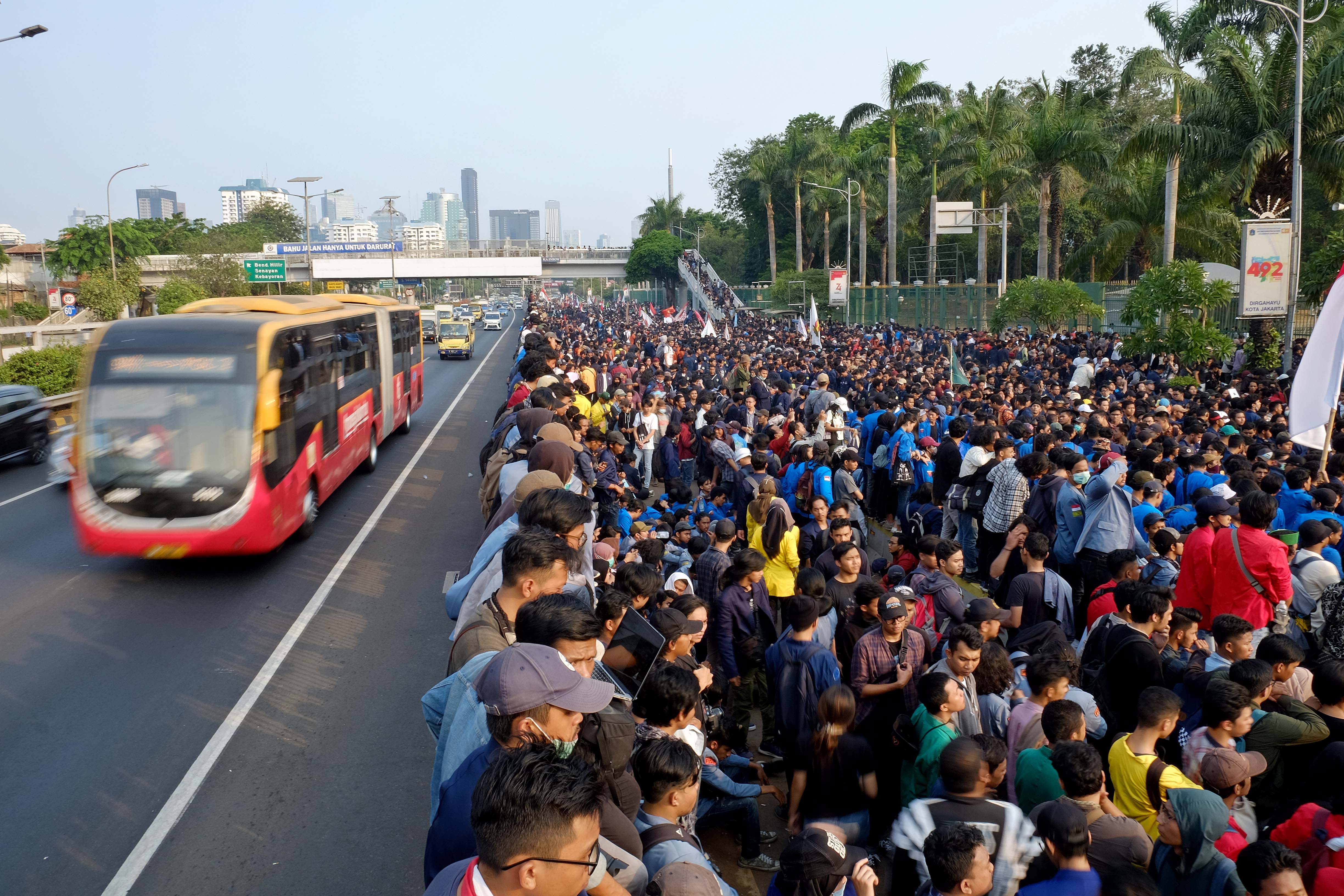 Bus Transjakarta melawati Jalan Gatot Subroto di depan Gedung DPR/MPR RI yang dipenuhi mahasiswa. Senin (23/9).