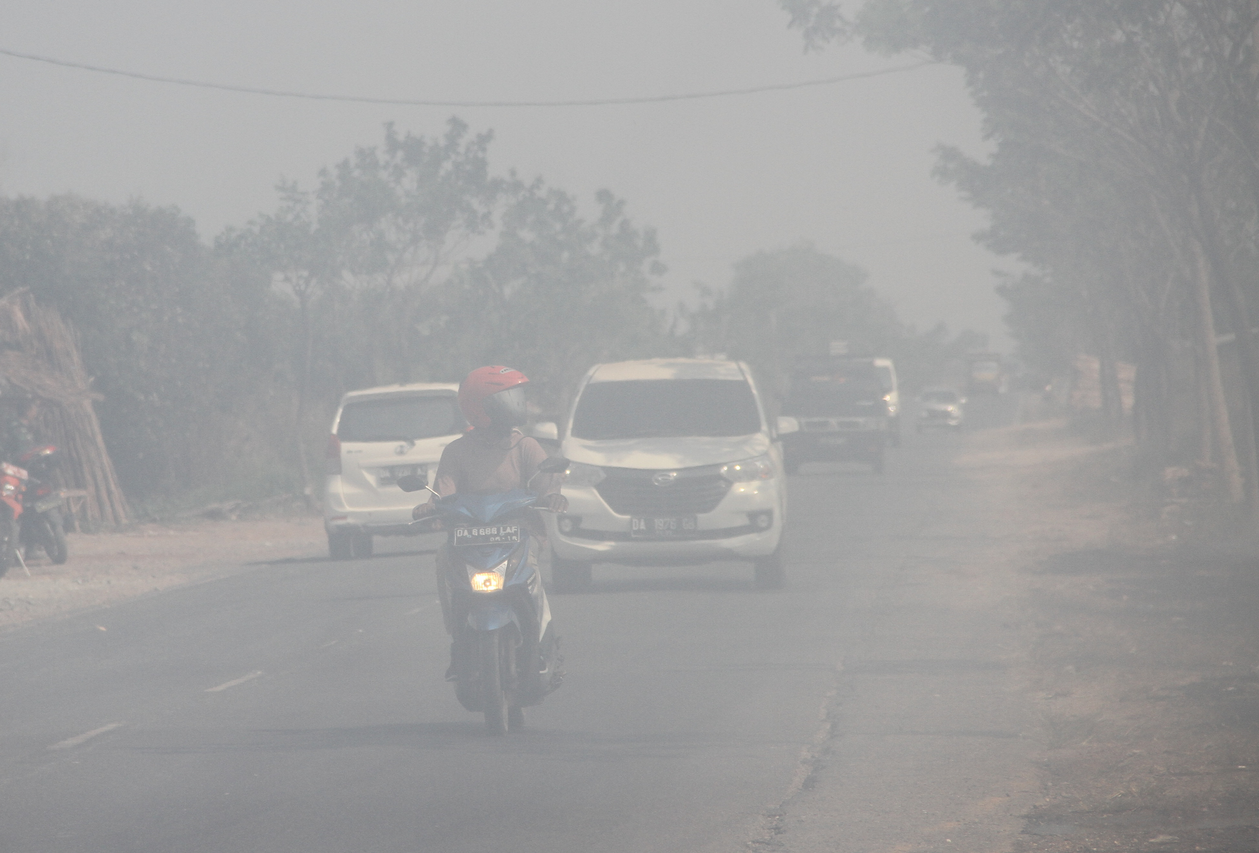  Sejumlah kendaraan bermotor melintas di jalan berselimut  asap dari kebakaran lahan gambut di Kecamatan Liang Anggang, Banjarbaru, Kalsel.