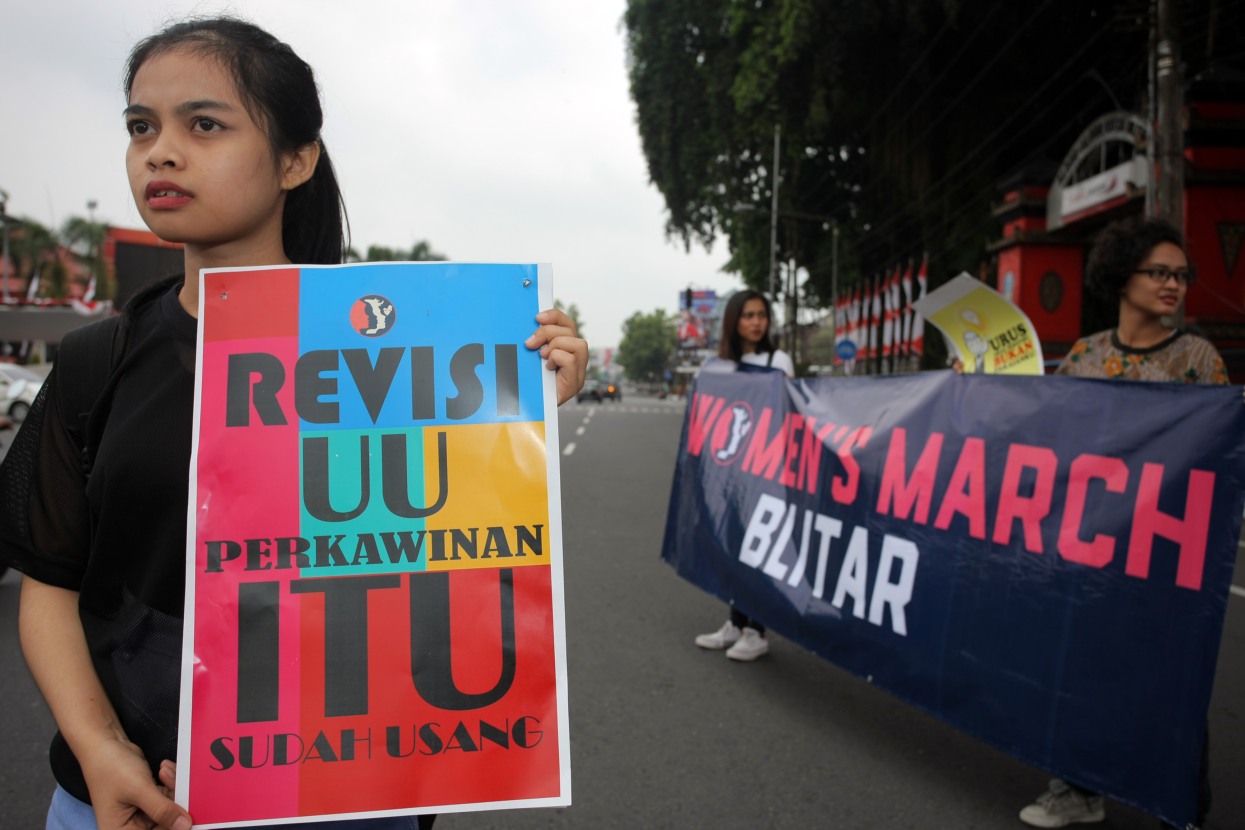  Aktivis membawa poster berisi tuntutan revisi UU Perkawinan saat menggelar aksi di Alun-alun Kota Blitar, Jawa Timur, Minggu (28/4/2019).