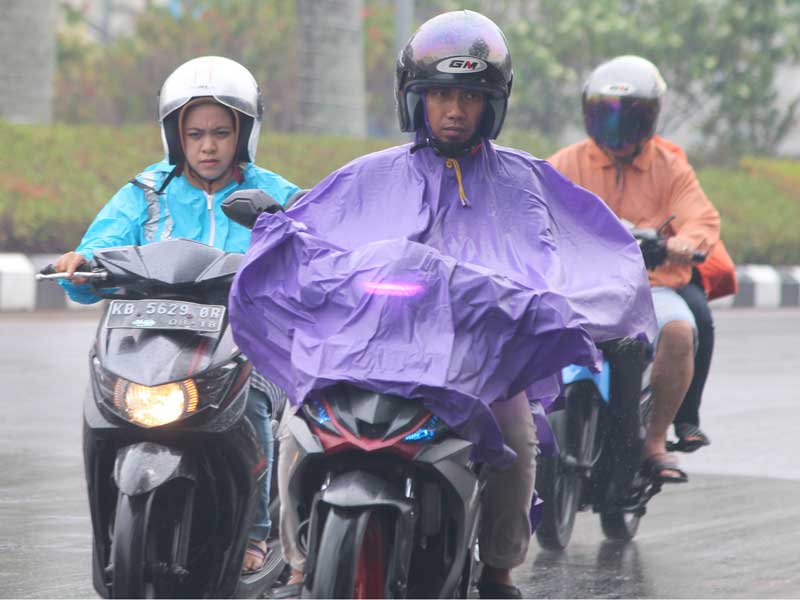 Pengendara sepeda motor melintasi Jalan Rahadi Oesman yang basah setelah hujan turun, di Pontianak, Kalimantan Barat, Senin (23/9/2019). 