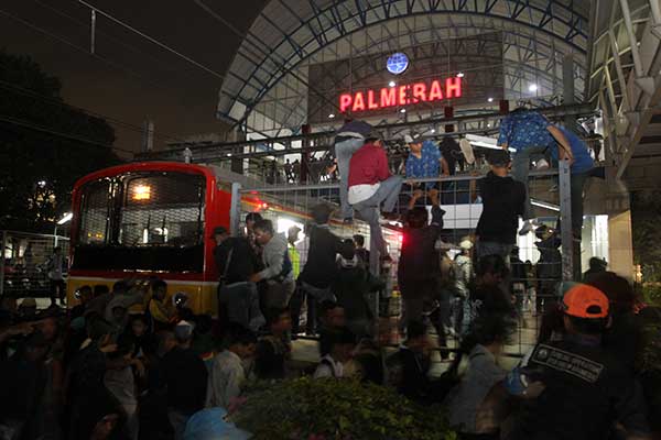 Calon penumpang KRL memanjat pagar pembatas untuk memasuki kereta di Stasiun Palmerah