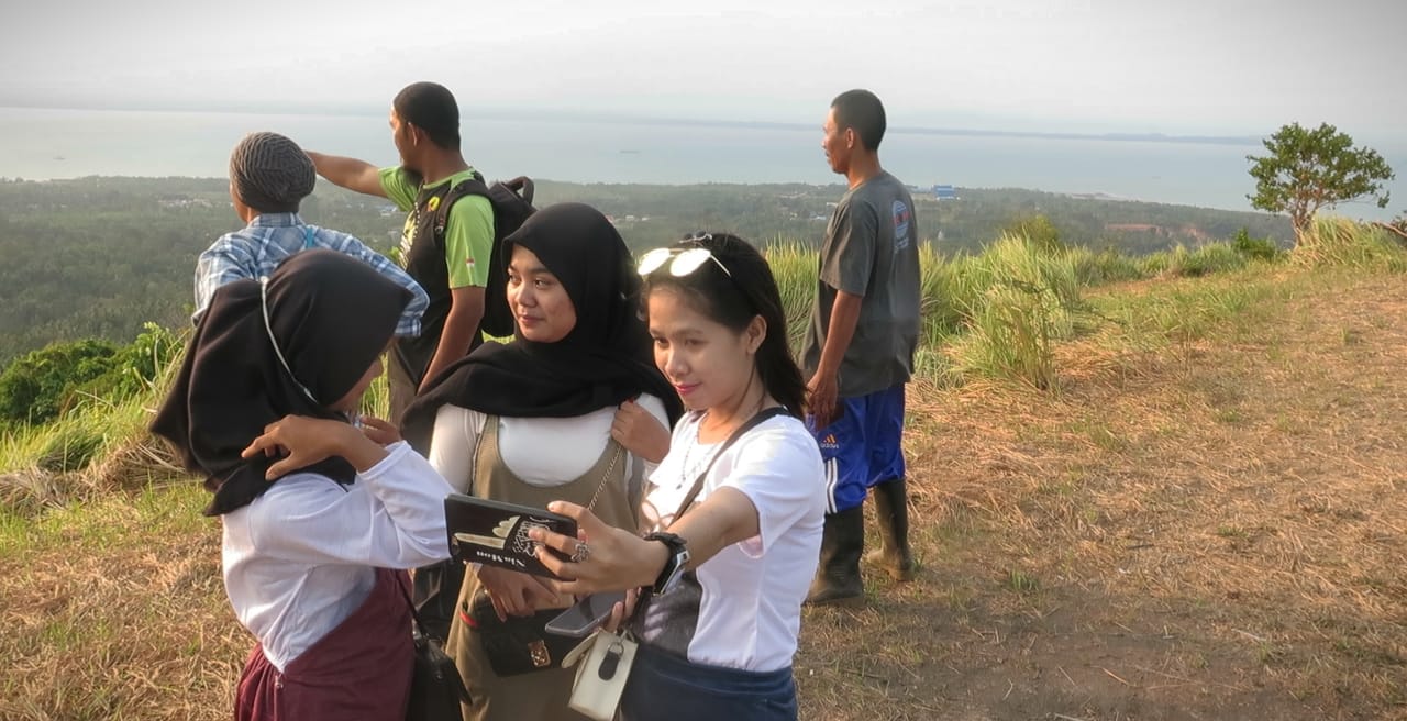 Wisatawan sedang berswafoto di Bukit Mamake, Pulau Laut, Kalsel. Bukit Mamake kini dijadikan tempat olahraga paralayang. 