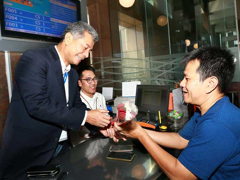 Direktur Utama BRI Sunarso (kiri) memberikan setangkai bungan Mawar pelanggan setelah melakukan transaksi di Kantor BRI, Jakarta, Rabu (4/9)