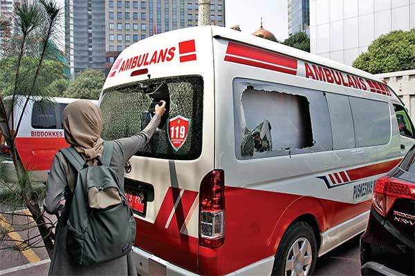 Seorang wartawan memotret ambulans milik Pemprov DKI Jakarta yang ditahan di halaman Polda Metro Jaya, Jakarta, kemarin.