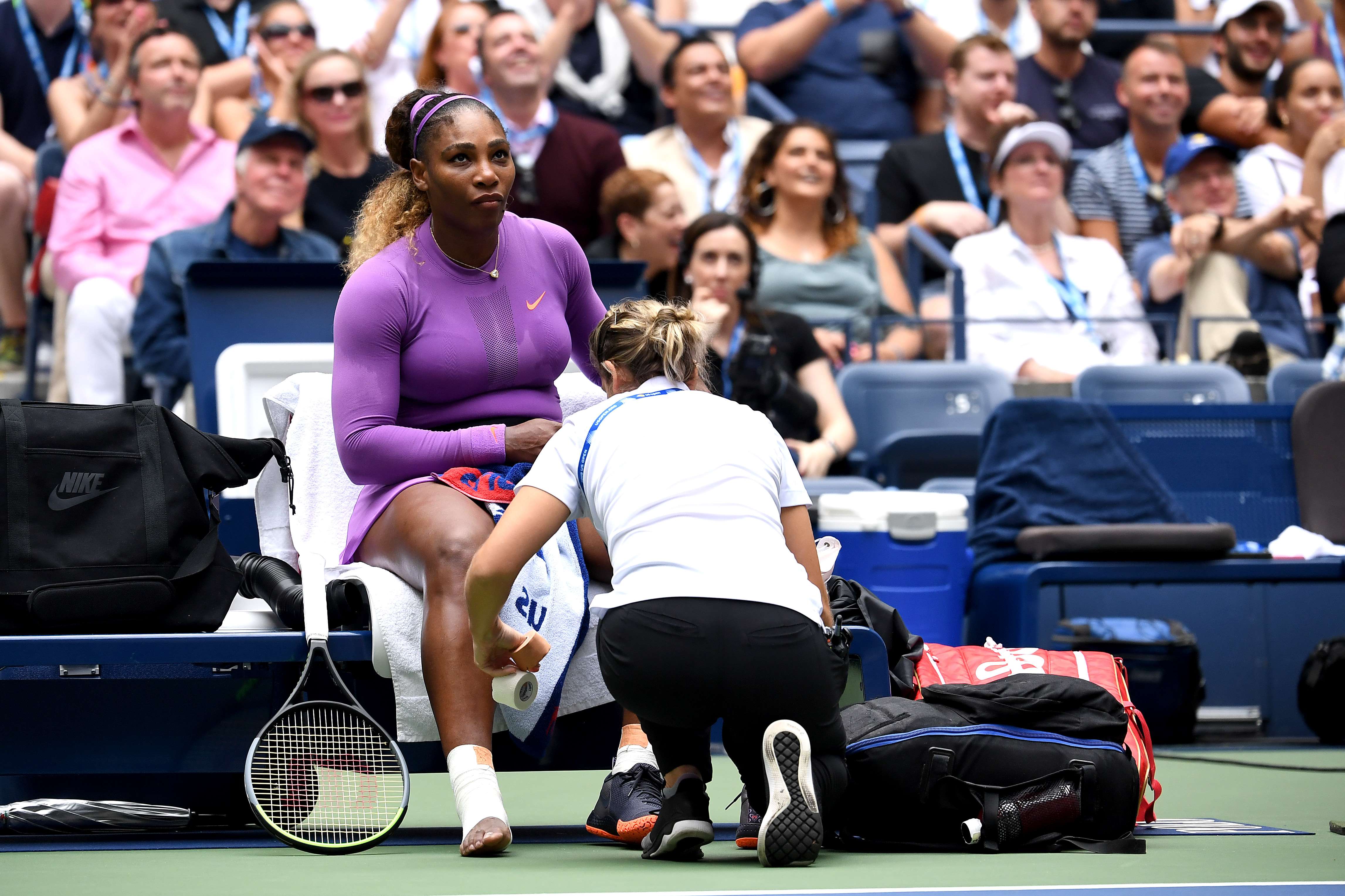 Petenis Serena Williams mendapatkan perawatan oleh tim medis. Pergelangan kakinya mengalami cedera saat bermain di babak kedua, Minggu (2/9)