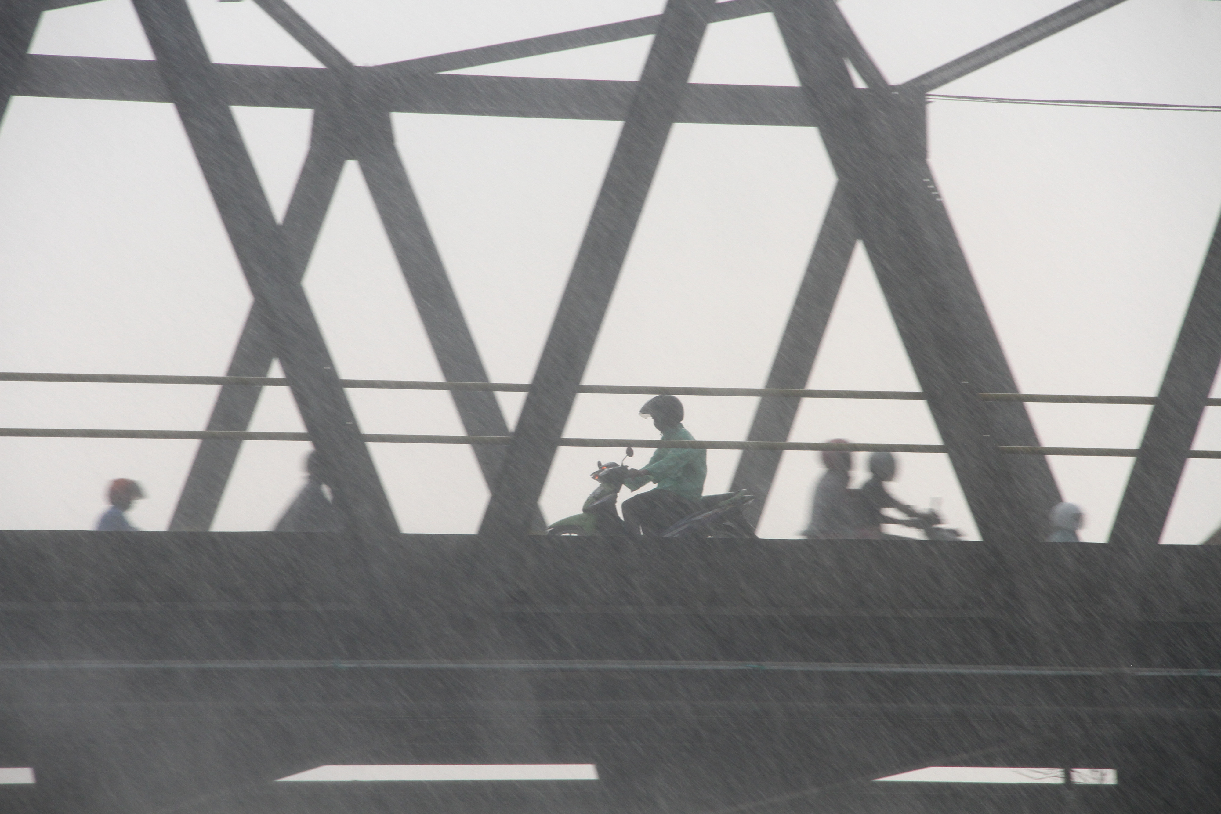 Pengendara sepeda motor menorobos hujan di Jembatan Banua Anyar, Banjarmasin, Kalimantan Selatan