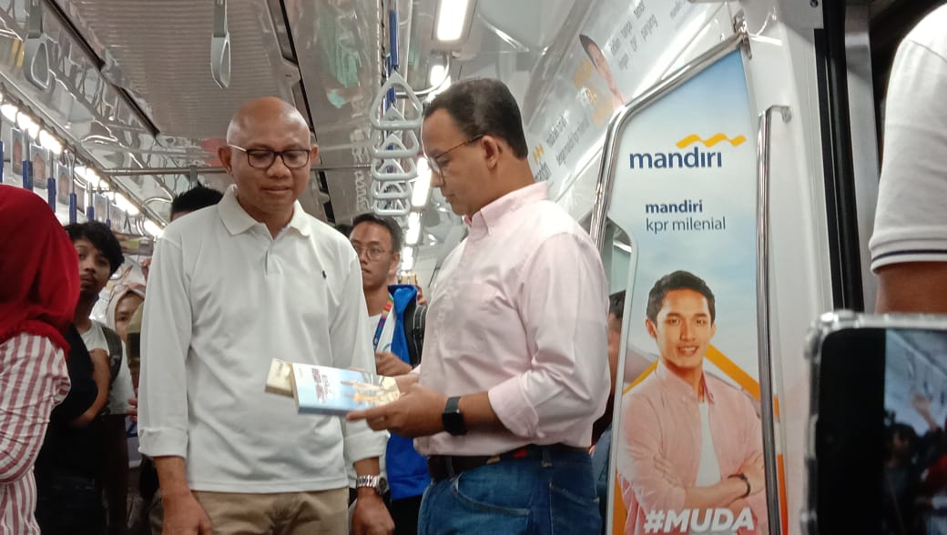 Gubernur DKI Jakarta Anies Baswedan (kanan) melihat buku yang diambil pengguna MRT dari book corner di stasiun