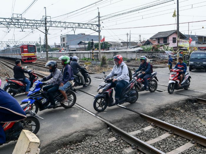Pengendara sepeda motor melintas di perlintasan sebidang kereta api.