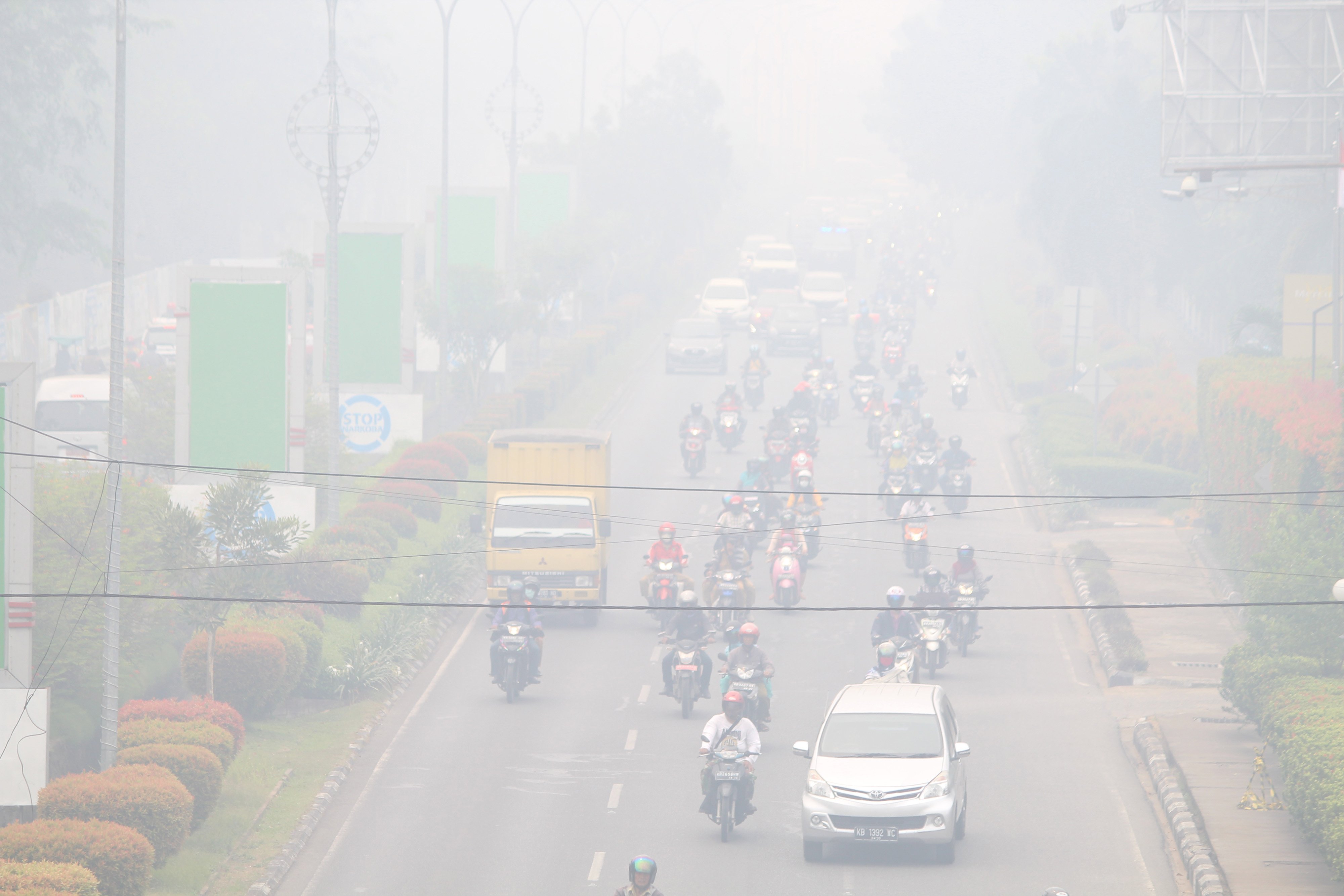 Sejumlah pengendara melintasi jalan yang diselimuti kabut asap di Pontianak, Kalimantan Barat, Senin (16/9)