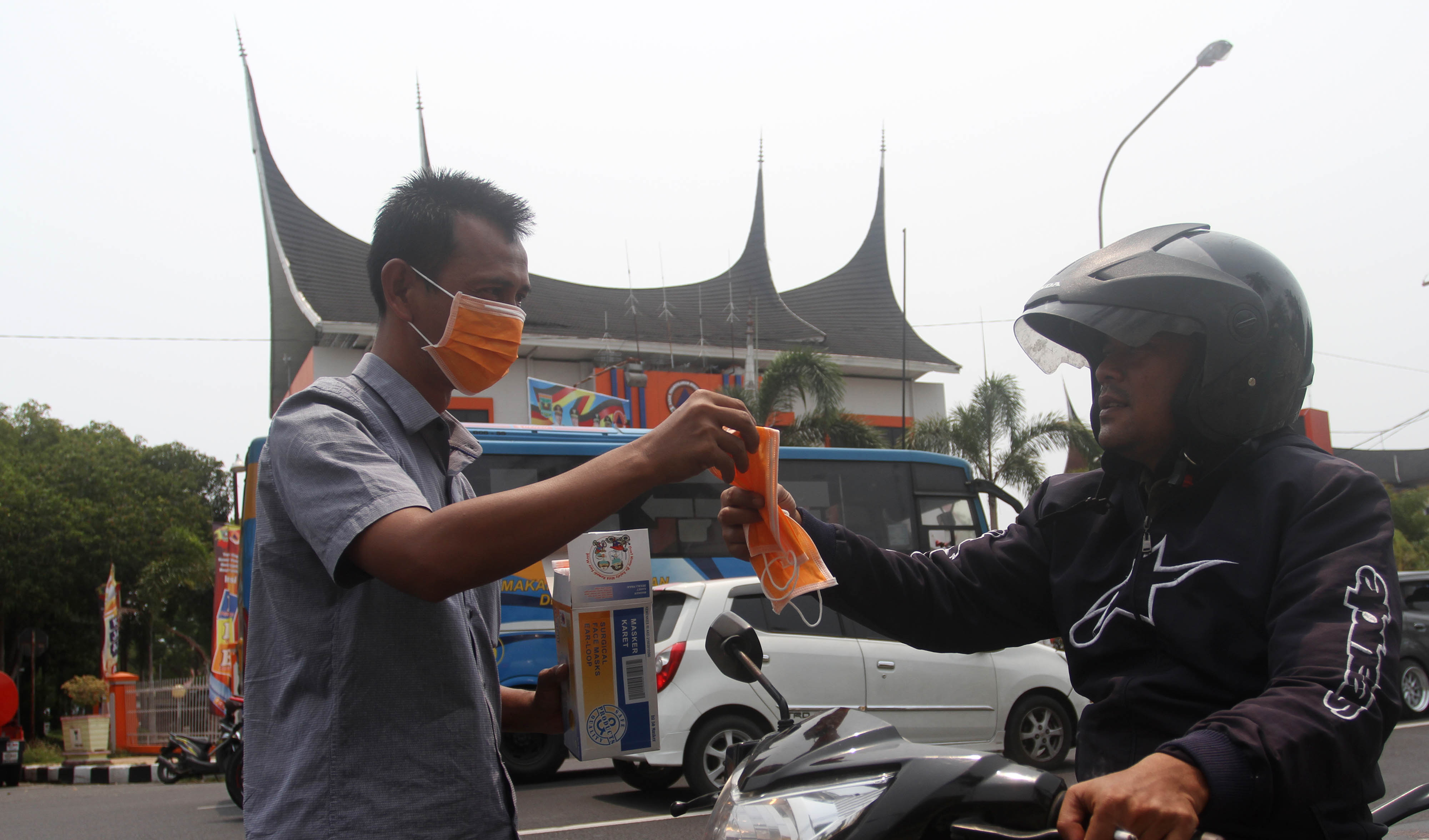 Petugas Badan Penanggulangan Bencana Daerah (BPBD) Sumatera Barat membagikan masker pada pengendara yang melintas di jalan Sudirman, Padang