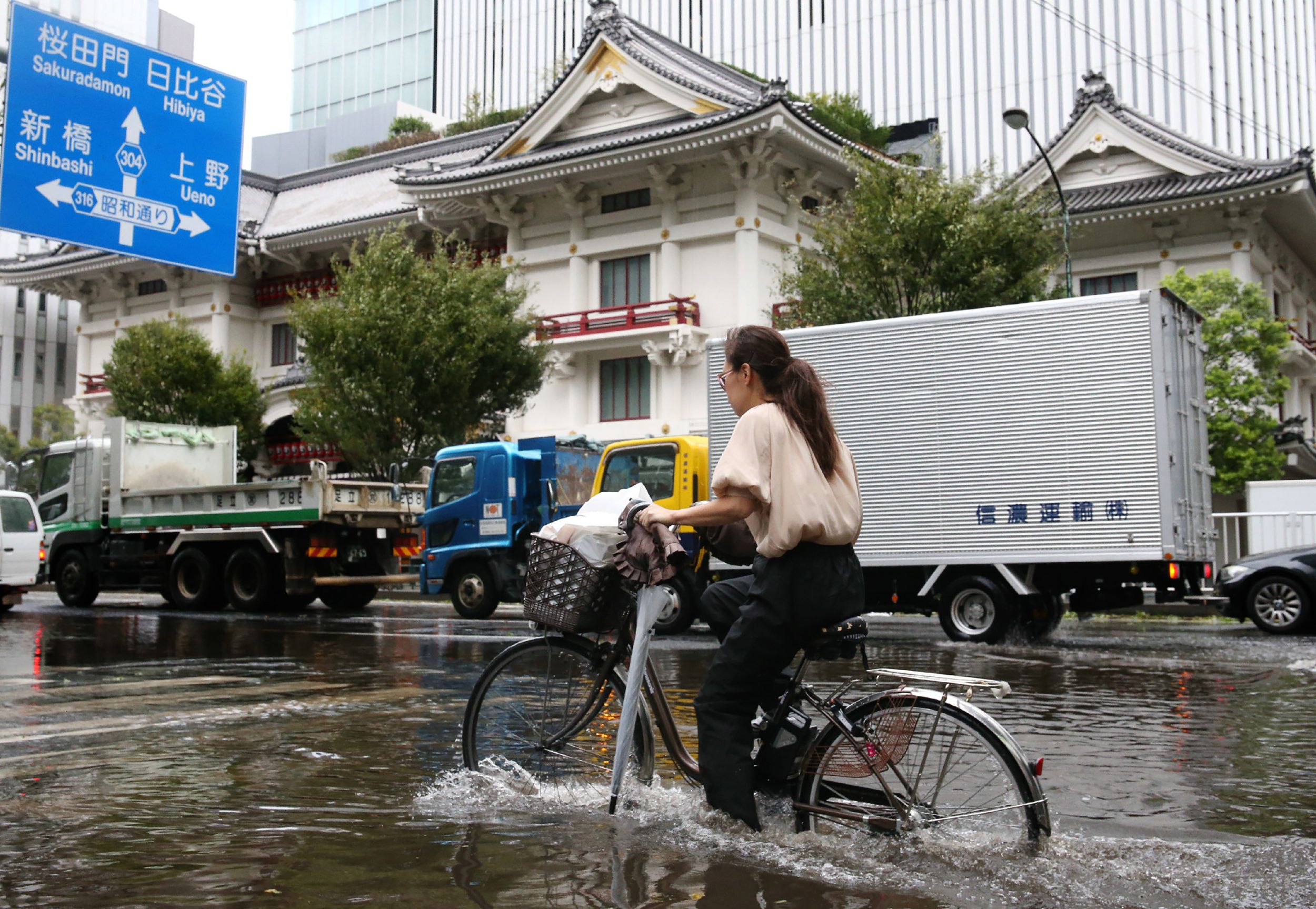 Seorang perempuan bersepeda melintasi jalan Kota Tokyo yang dilanda banjir saat Badai Faxai mendekat.