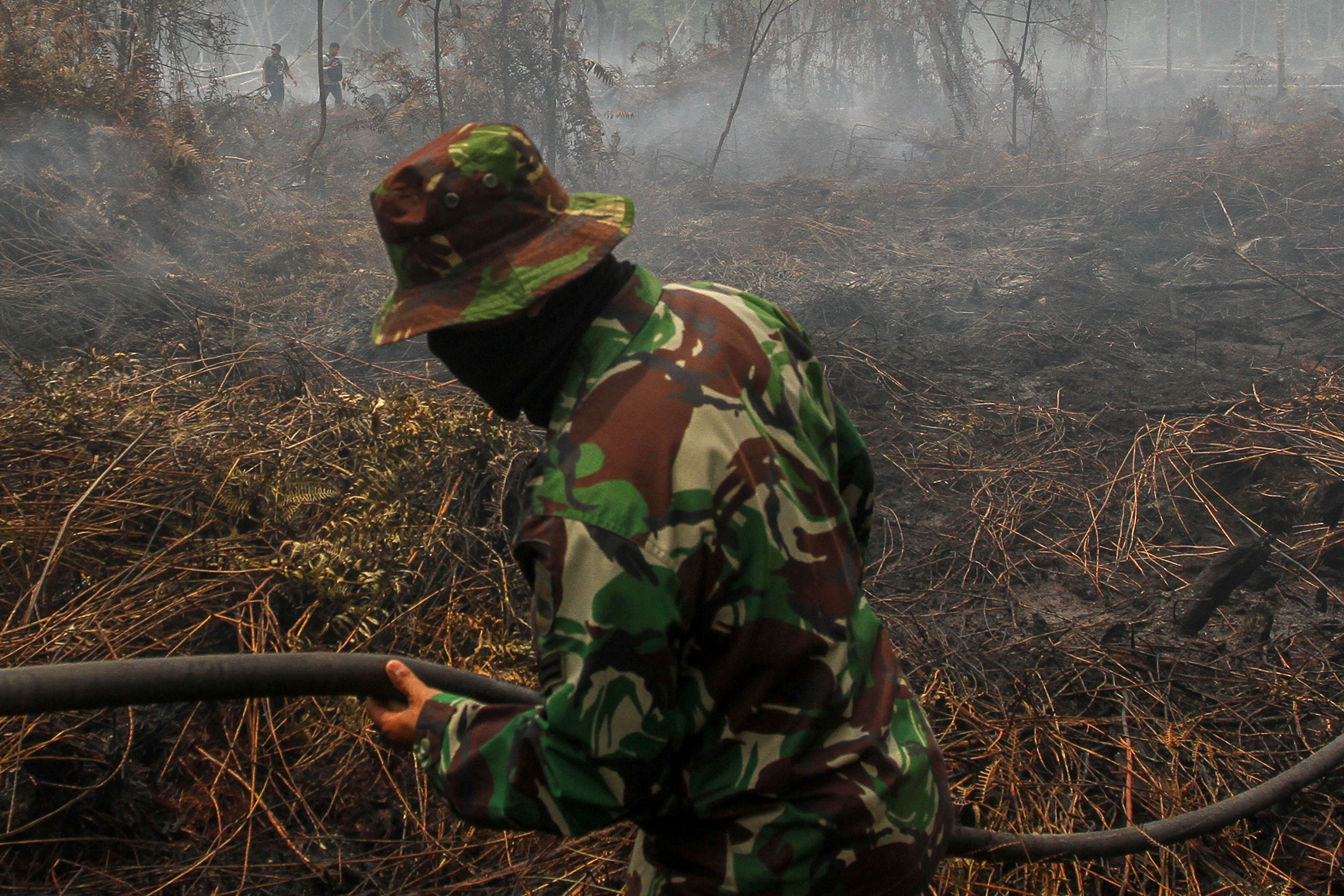 Personel TNI bersiap memadamkan bara api lahan gambut yang terbakar di Kecamatan Payung Sekaki, Pekanbaru, Riau.