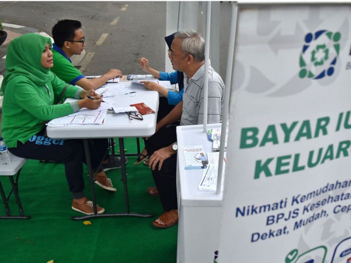 Petugas Badan Penyelenggara Jaminan Sosial (BPJS) Kesehatan memberikan informasi kepada warga mengenai JKN-KIS. 