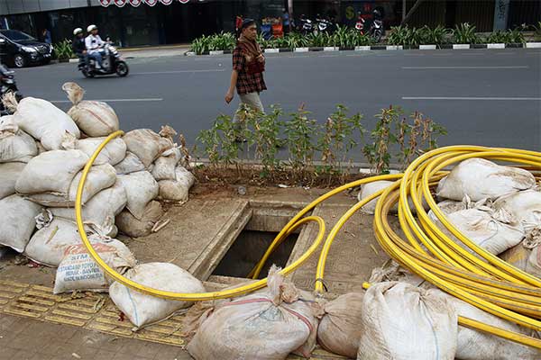 Ilustrasi -- Pejalan kaki melintasi galian fiber optik yang tidak tertutup di trotoar Jalan Melawai, Jakarta, Jumat (23/8).