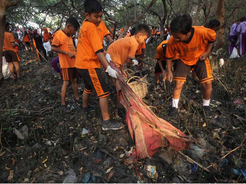 Pelajar memungut sampah yang berserakan di sekitar kawasan pantai di Tambak Wedi, Surabaya, Jawa Timur.