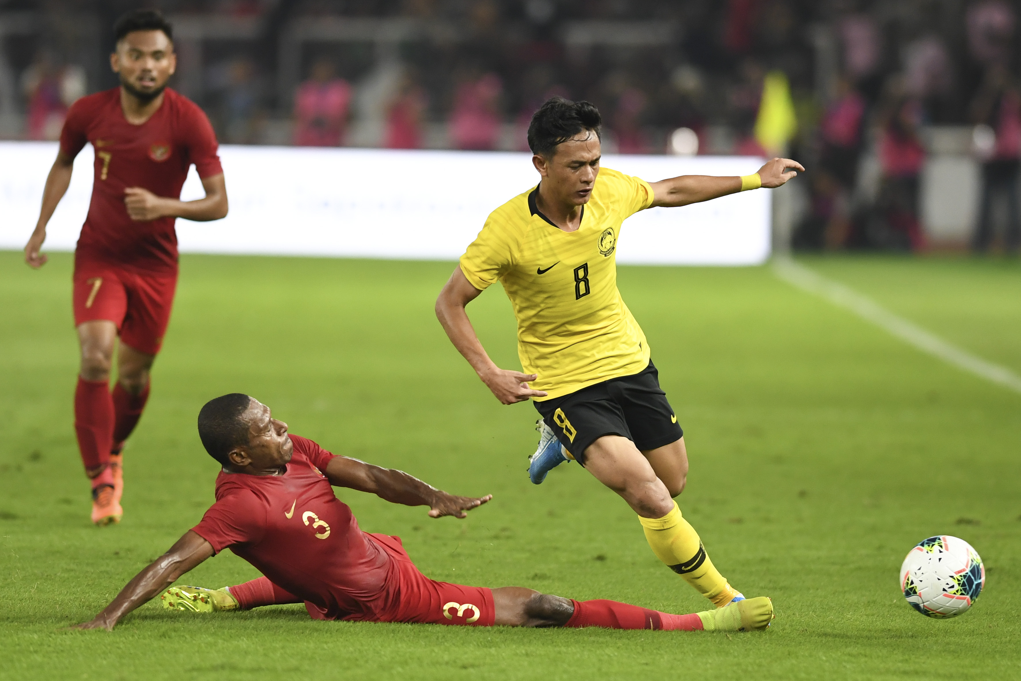 Pemain Timnas Indonesia Yustinus Paew (bawah) berusaha merebut bola dari pemain Timnas Malaysia Muhamad Nor Azam (kanan).