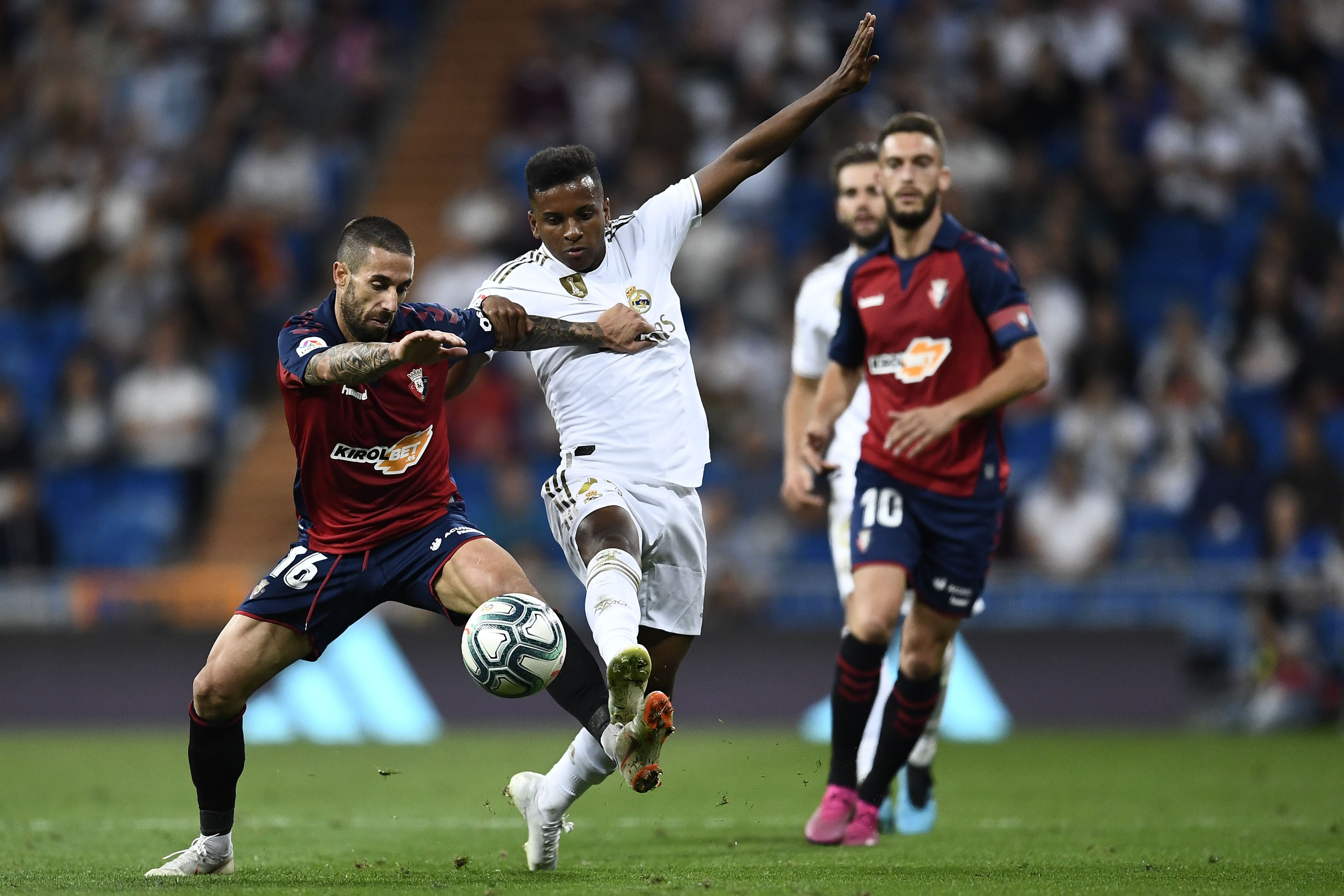 Bek Osasuna Lillo Castellano (kiri) menempel penyerang Real Madrid Rodrygo (tengah) saat laga yang berlangsung di Stadium Santiago Bernabeu.