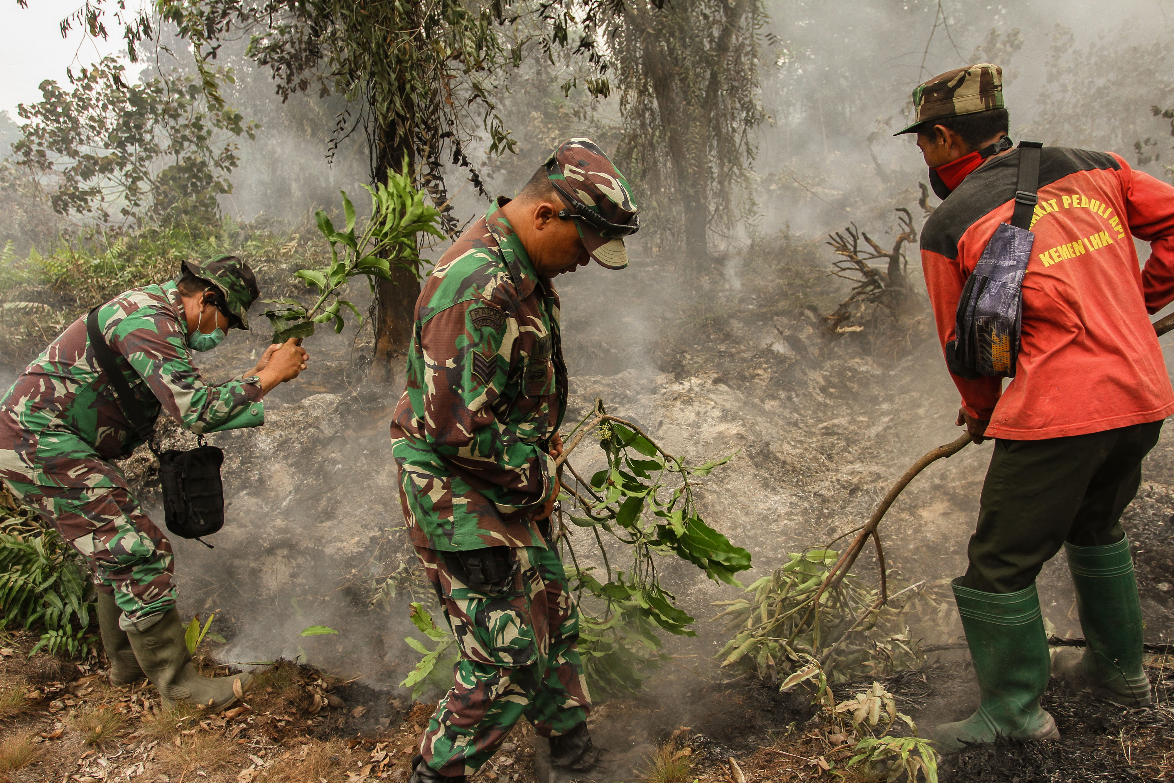  Prajurit TNI dari Kodim 0301 Kota Pekanbaru dibantu Masyarakat Peduli Api (MPA) berusaha menghalau api yang membakar semak belukar  