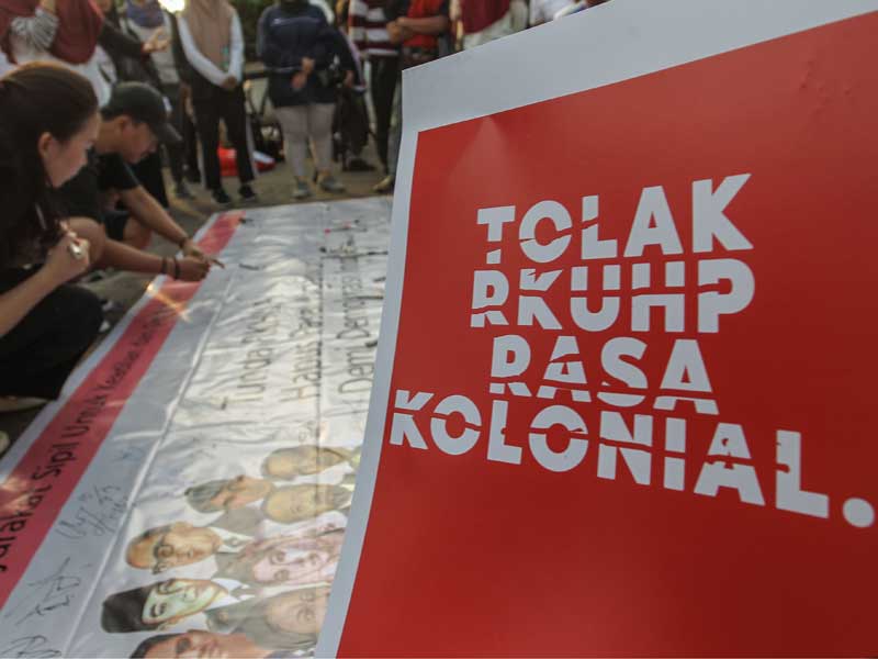 Warga membubuhkan tanda tangan pada spanduk sebagai bentuk dukungan pada aksi tolak RUU KUHP.