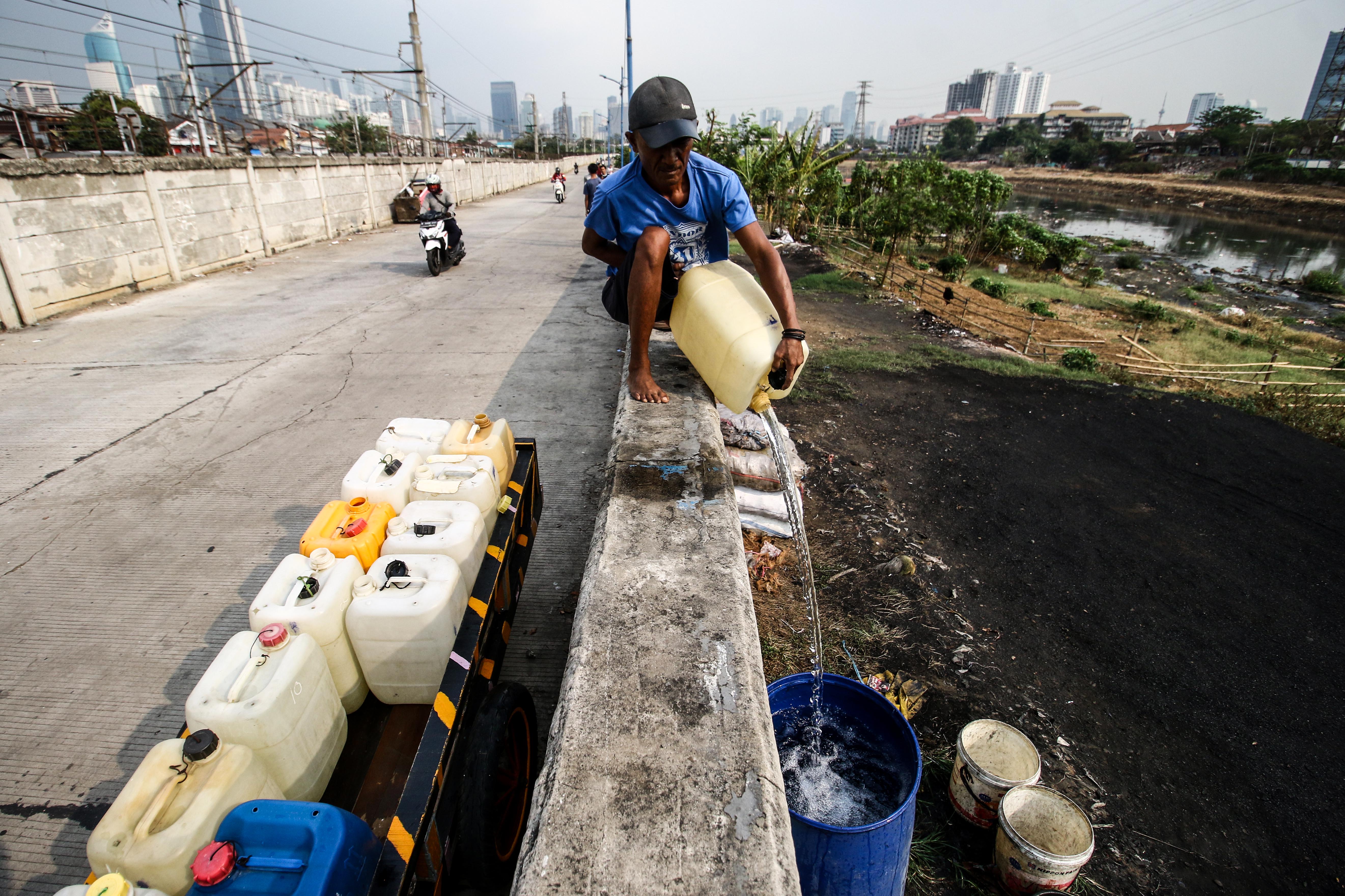 Warga mengisi air kedalam tong dengan menggunakan jeriken di Banjir Kanal Barat, Jakarta, Kamis (22/8)