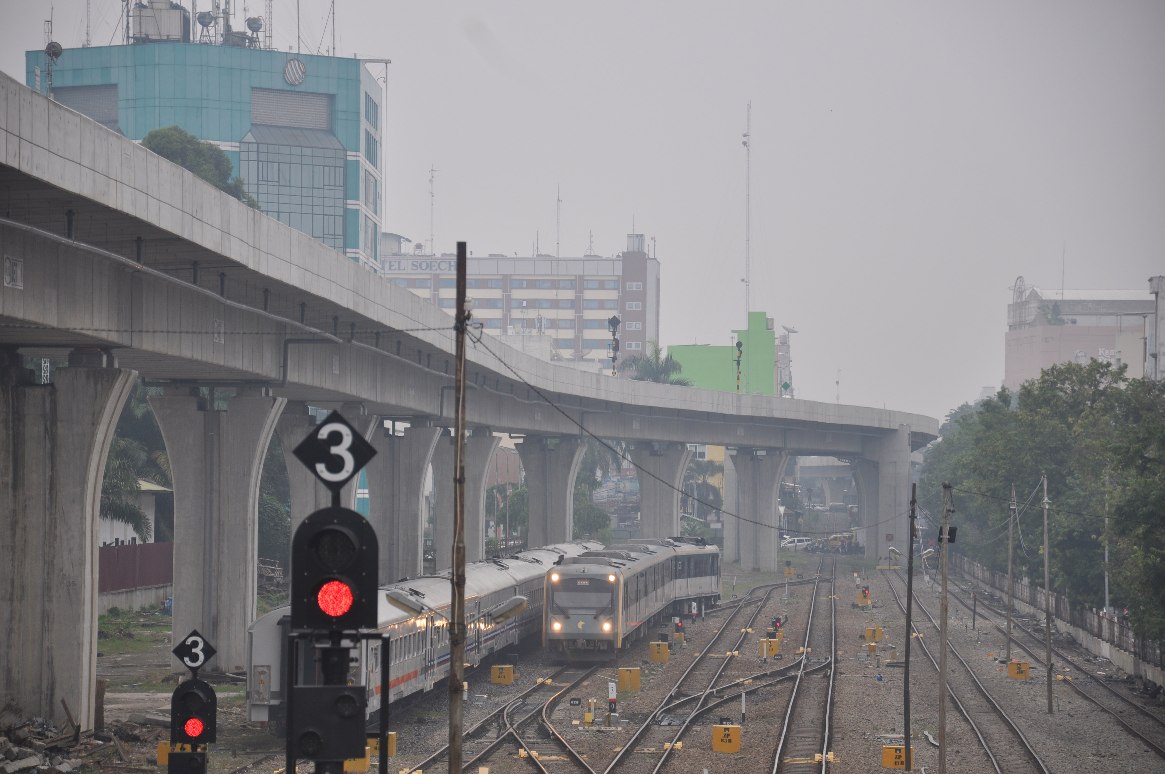 Sebuah kereta api Railink bandara Kualanamu melintas dengan latar belakang kota Medan yang diselimuti kabut asap di Sumatra Utara