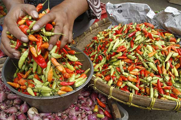 Ilustrasi -- Pedagang sayur menimbang cabe rawit