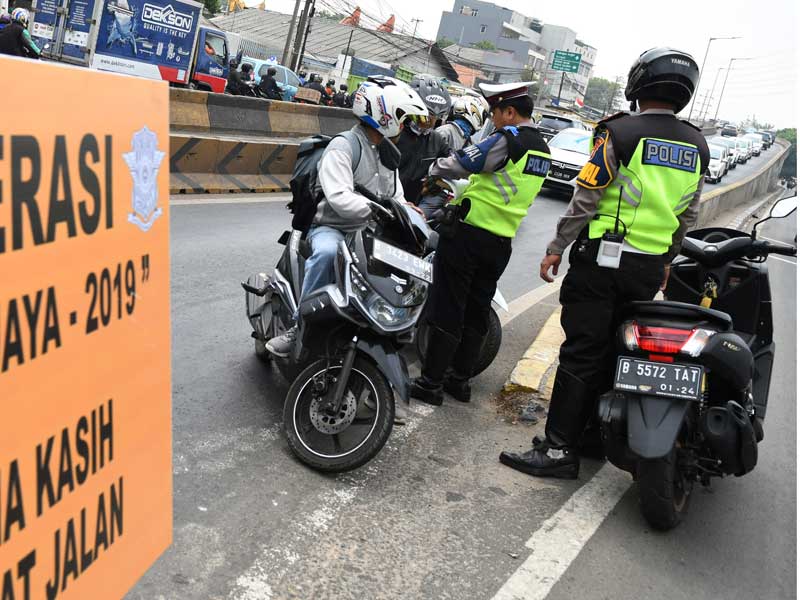 Polisi Lalu lintas menilang pengendara sepeda motor yang melintas di Jalan Layang Pesing, Jakarta.