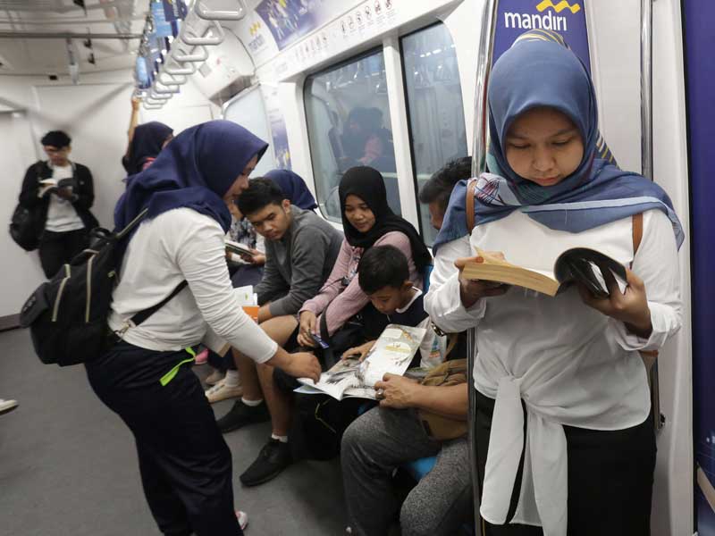 Penumpang MRT mengisi waktu perjalanan dengan membaca buku yang tersedia di pojok buku Stasiun MRT Bundaran HI, Jakarta.