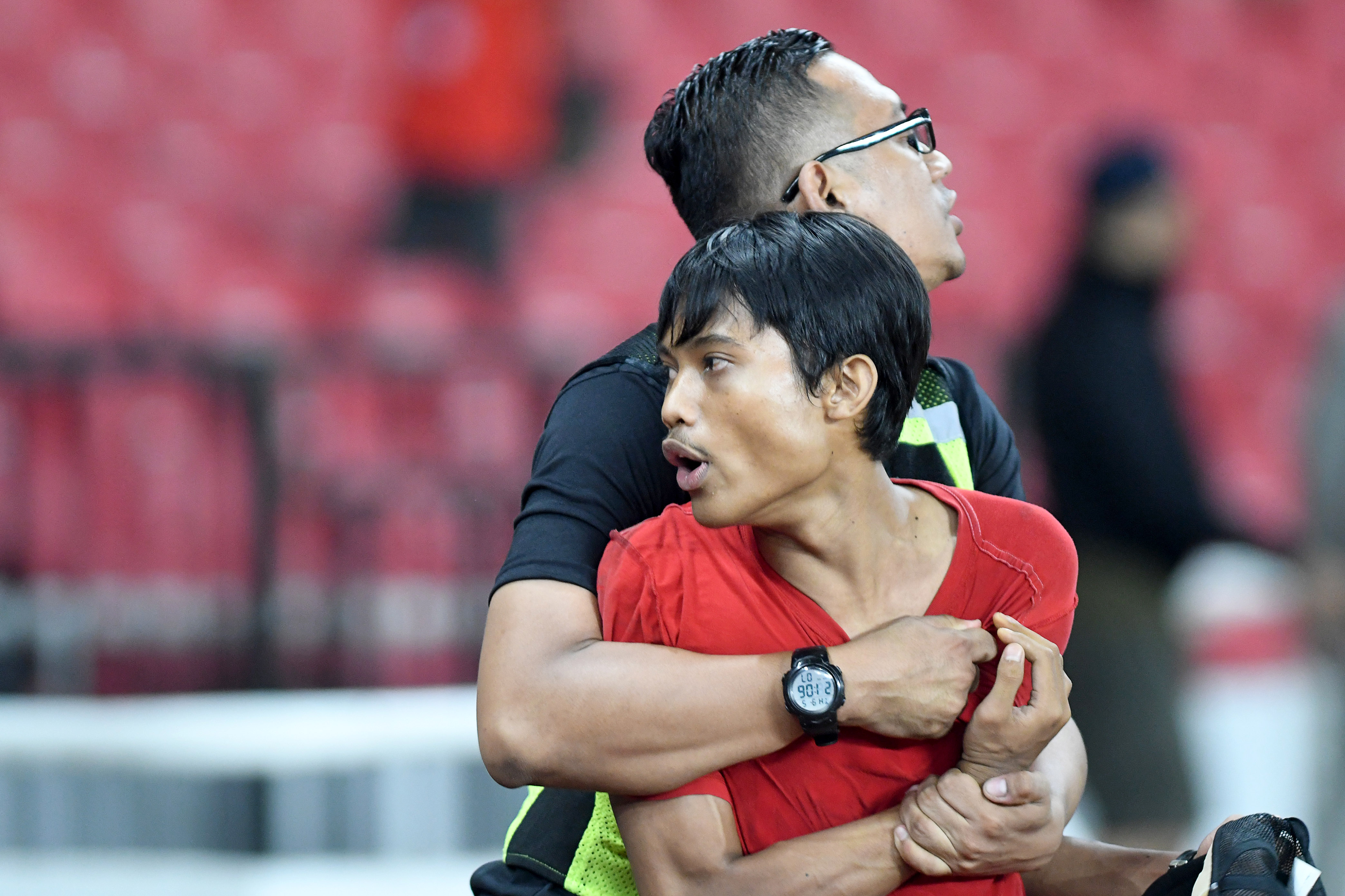 Seorang suporter Indonesia (kanan) diamankan petugas seusai berusaha menyerang suporter Malaysia.