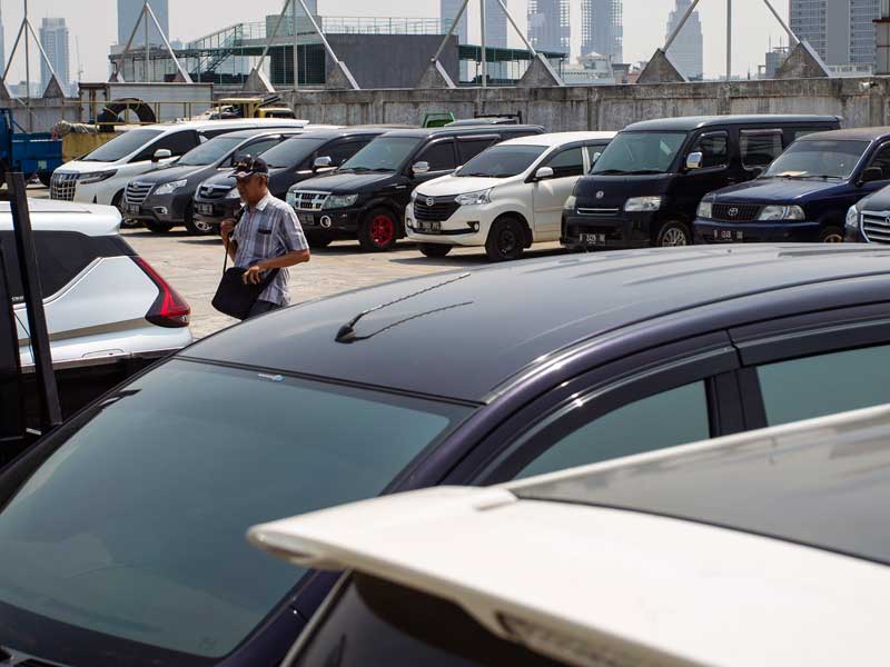 Pengunjung berjalan diantara kendaraan yang terparkir di salah satu pusat perbelanjaan di Jakarta.
