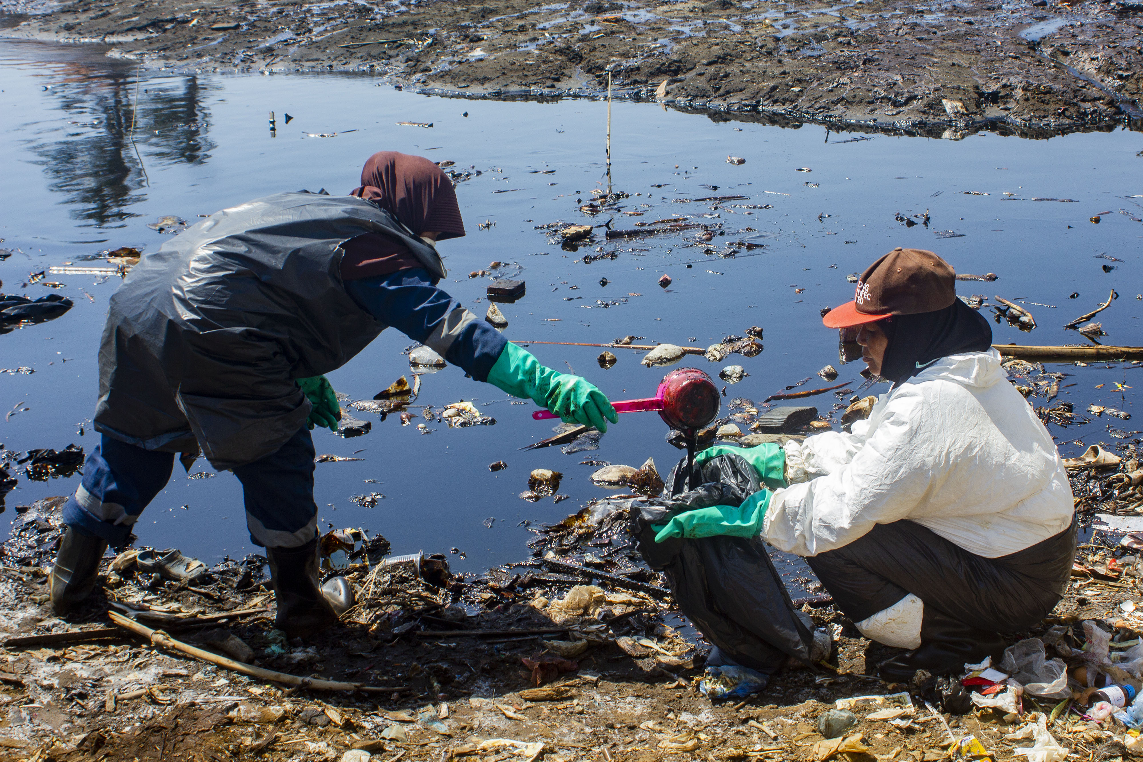  Petugas mengumpulkan tumpahan minyak mentah di Desa Cemarajaya, Cibuaya, Karawang, Jawa Barat, Jumat (30/8).