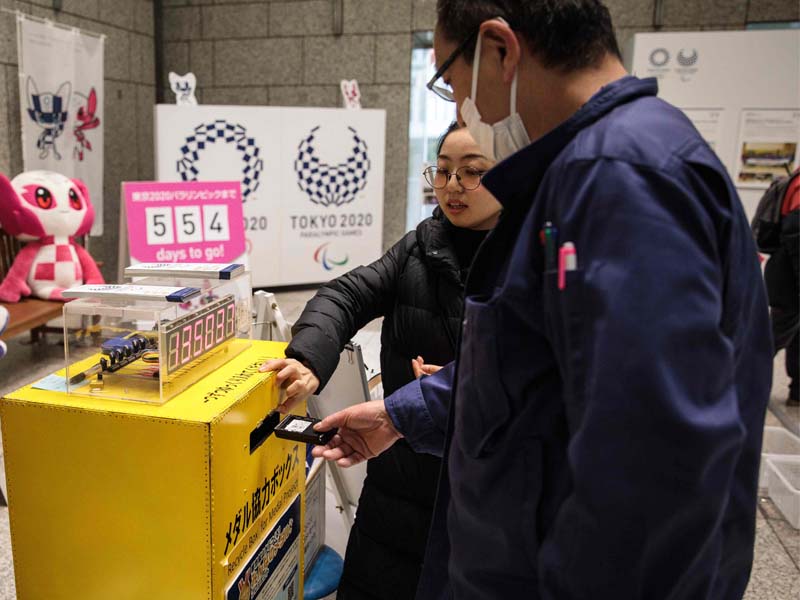 Warga Jepang memasukkan sampah elektronik di kotak sumbangan yang kemudian akan didaurulang menjadi medali.