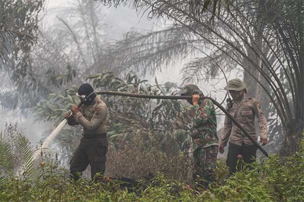 Petugas berusaha memadamkan kebakaran lahan di Kabupaten Pelalawan, Riau, Kamis (19/9/2019). 