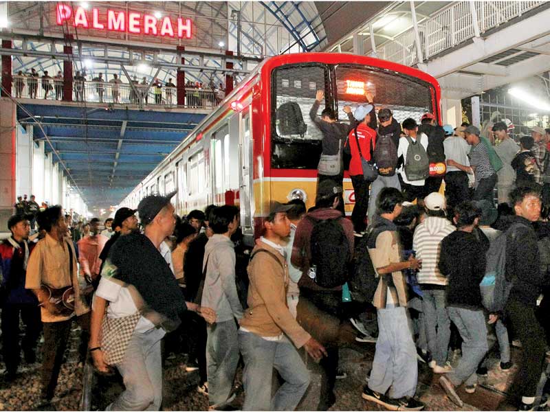 Calon penumpang kereta rel listrik (KRL) Commuter Line memanjat pagar pembatas untuk memasuki gerbong kereta pada pukul 18.53 WIB di Stasiun
