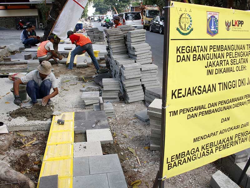 Pekerja tengah mengerjakan proyek revitalisasi pelebaran trotoar untuk pejalan kaki.
