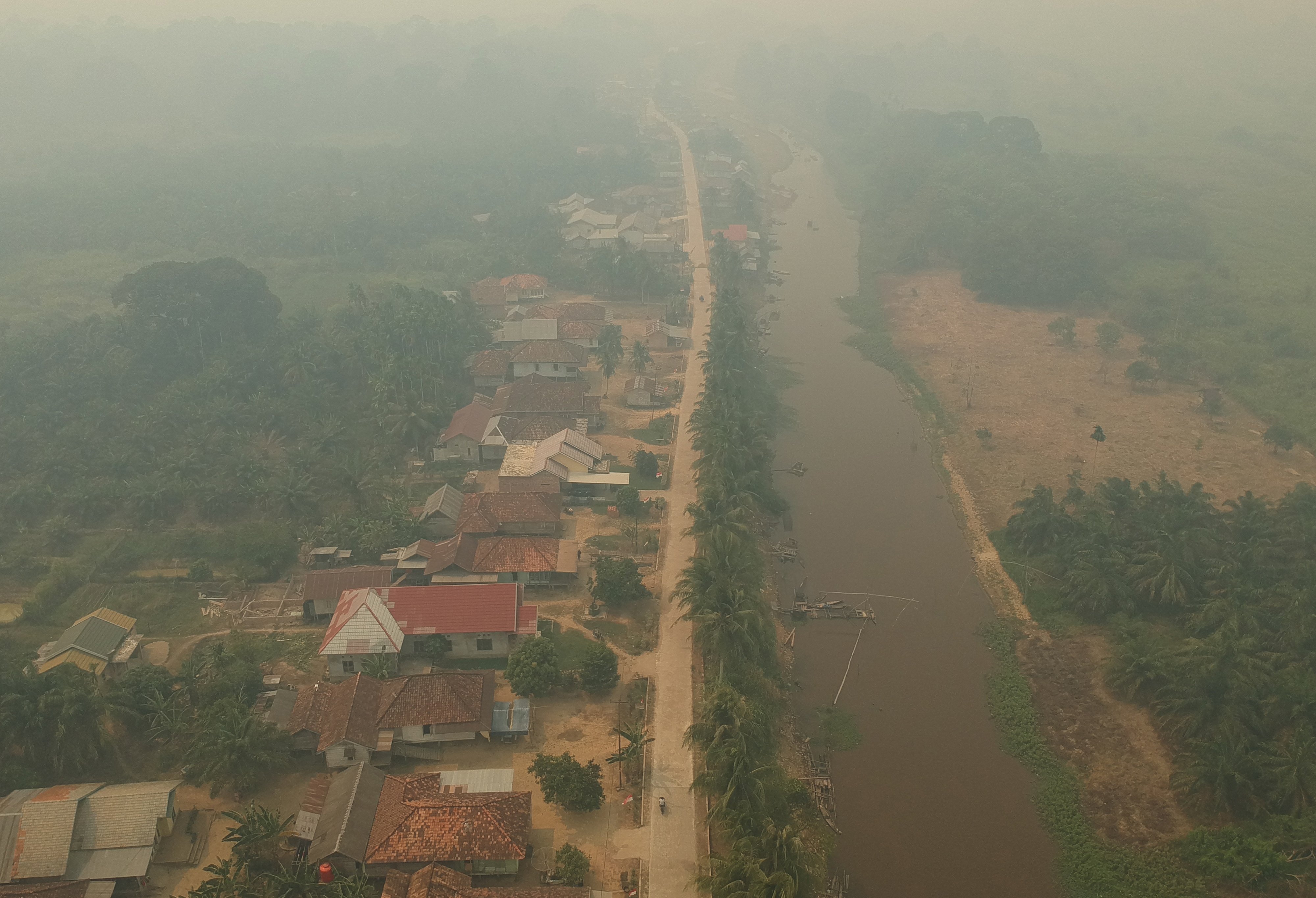 Foto udara kawasan permukiman penduduk yang diselimuti kabut asap di Arang-arang, Kumpeh Ulu, Muarojambi, Jambi.