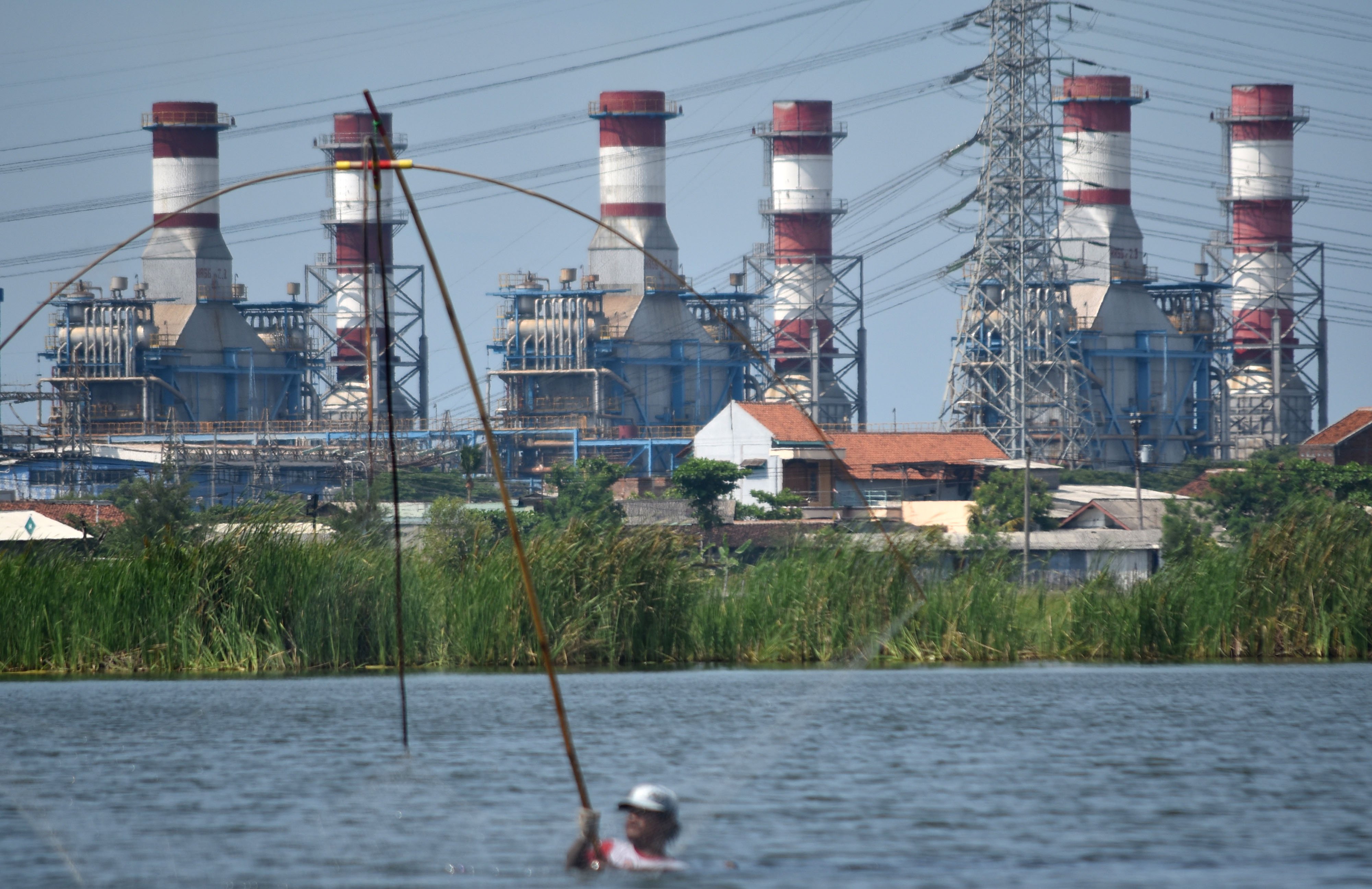 Warga beraktivitas dengan latar belakang Pembangkit Listrik Tenaga Gas-Uap (PLTGU) Tambak Lorok di Semarang, Jawa Tengah.