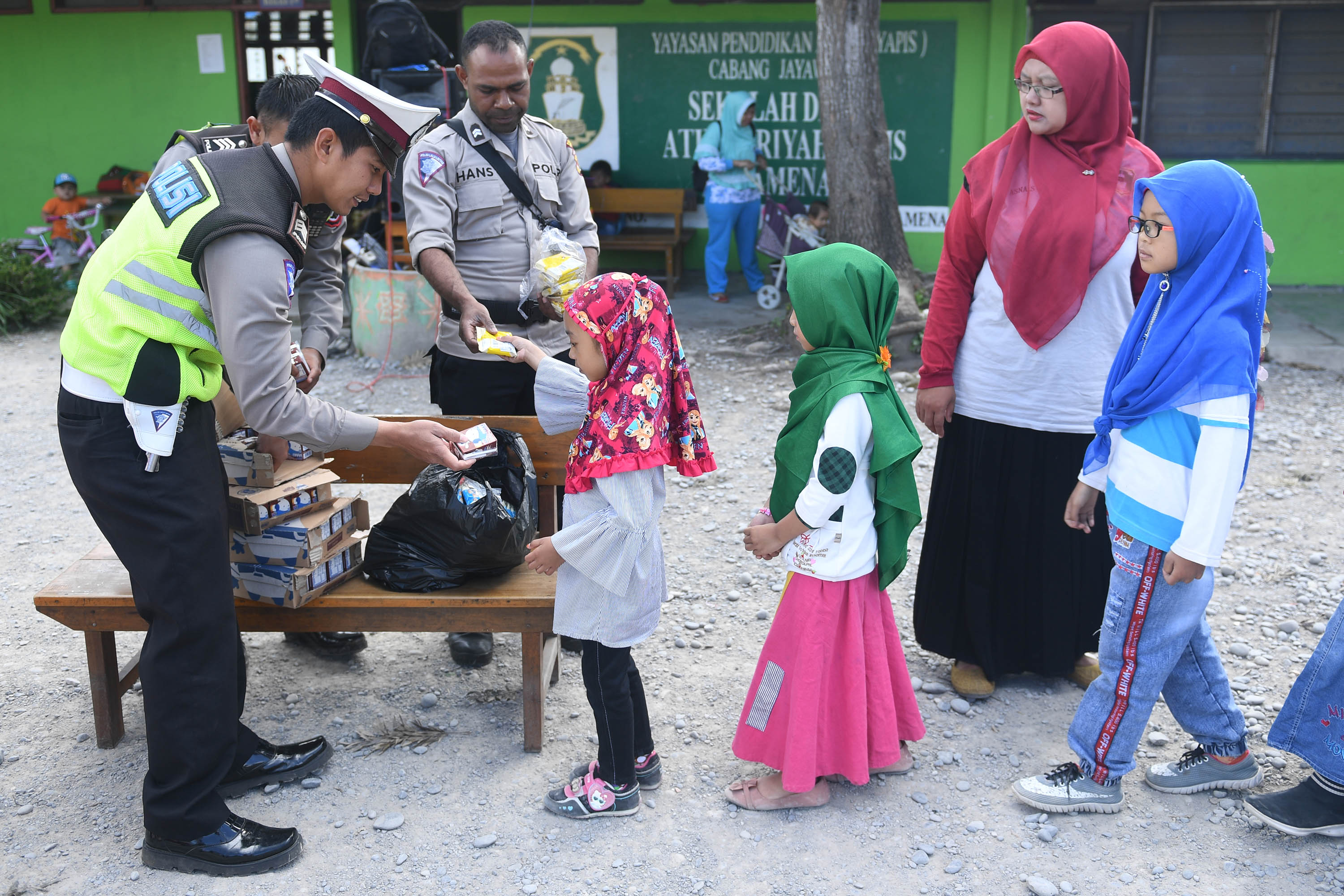 Anggota polisi membagikan makanan ringan pada siswa SD Yayasan Pendidikan Islam (Yapis) Wamena, Kabupaten Jayawijaya, Papua.