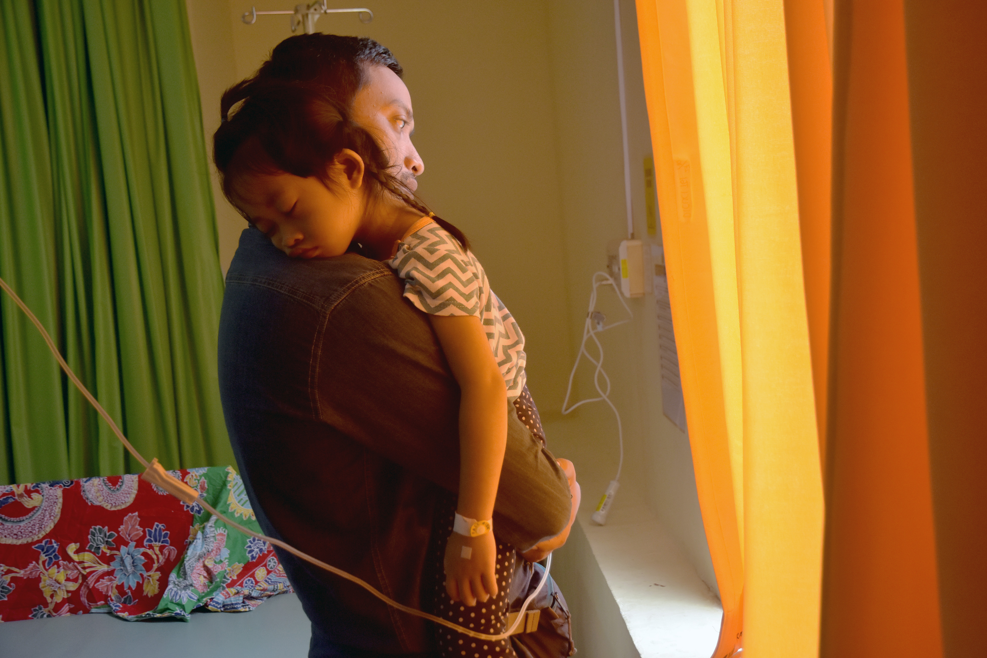 Seorang anak yang menderita sesak nafas akibat asap karhutla tertidur di pelukan ayahnya di RSIA Eria Bunda, Kota Pekanbaru, Riau