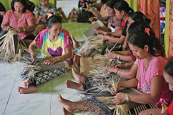 Para anggota kelompok perajin anyaman rotan tengah menyelesaikan anyaman berbentuk tas di
