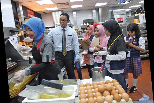 Repcil mendengarkan dan mencatat informasi saat berkunjung ke dapur McDonald’s.